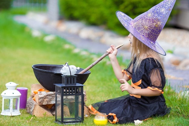 Happy little witch have fun outdoors on Halloween. Trick or treat.