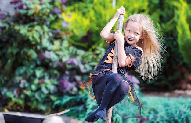 Happy little witch have fun outdoors on Halloween. Trick or treat.