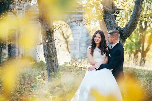 Happy and in love bride and groom walk in autumn park on their wedding day