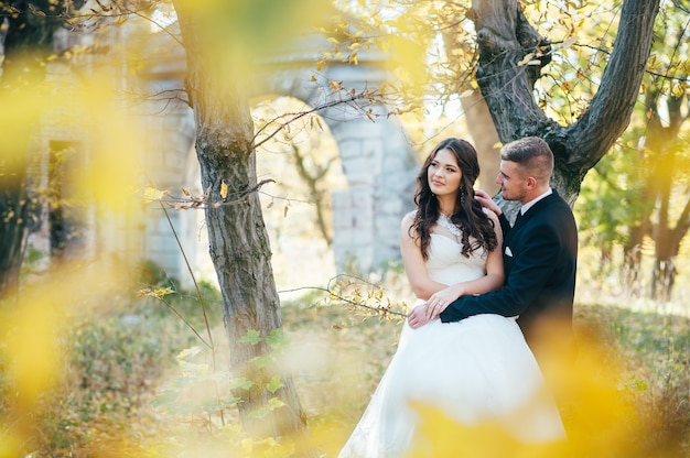 Happy and in love bride and groom walk in autumn park on their wedding day