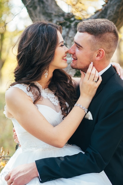 Happy and in love bride and groom walk in autumn park on their wedding day