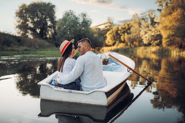 Photo happy love couple boating on lake at summer day. romantic date, boat trip, man and woman walking along the river