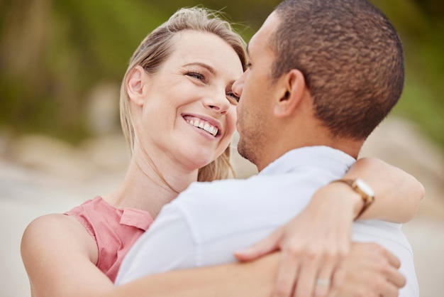 A happy love and diversity couple hug outside on their honeymoon vacation or holiday Man and woman together in relationship embrace romantic bond and loving on a sunny day celebrate anniversary