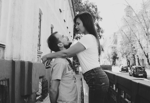 A happy loving couple look into each other's eyes in the city street A young woman embraces a man putting her hands on his shoulders