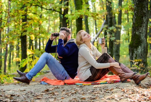 Happy loving couple relaxing in park together Couple in love tourists relaxing picnic blanket Man with binoculars and woman with metal mug enjoy nature park Park date Relaxing in park together