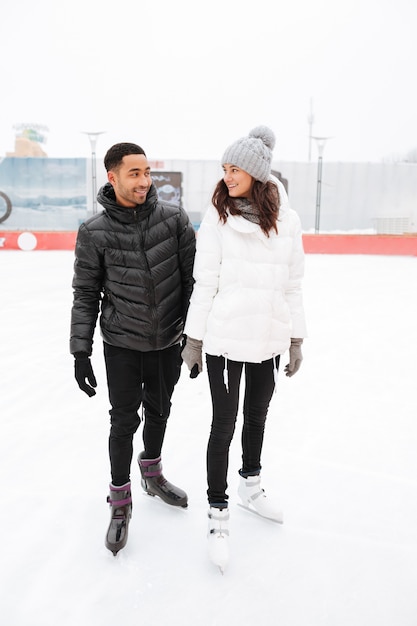 Happy loving couple skating at ice rink outdoors