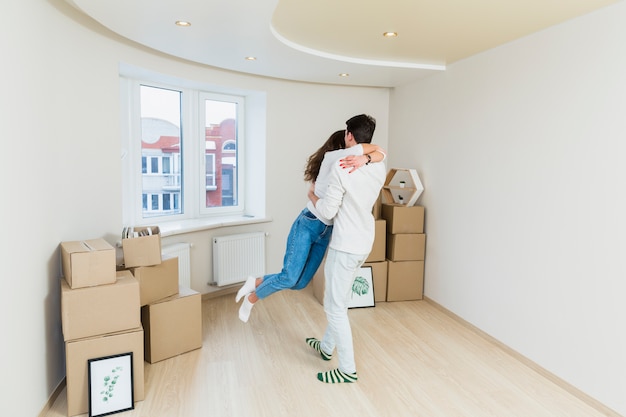 Happy loving couple with cardboard boxes in new house at moving day