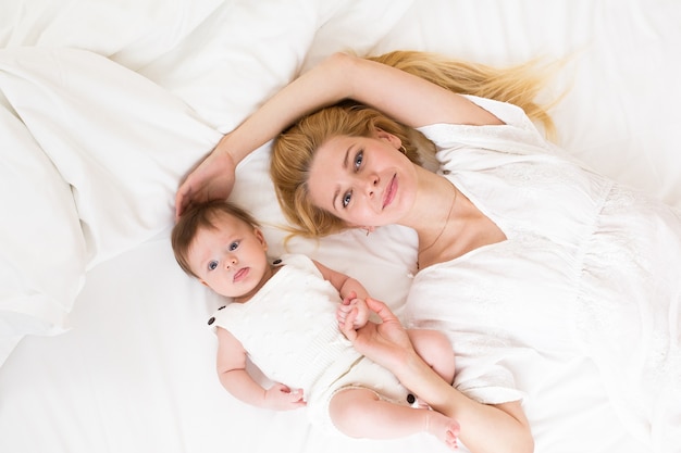 Happy loving family. mother playing with her baby in the bedroom, view from above.