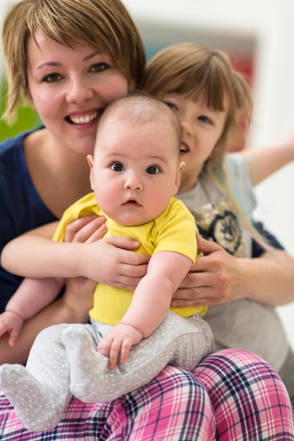 Happy loving family. portrait of young mother with  her kids little girl and baby boy hugging each other while spending time together at home