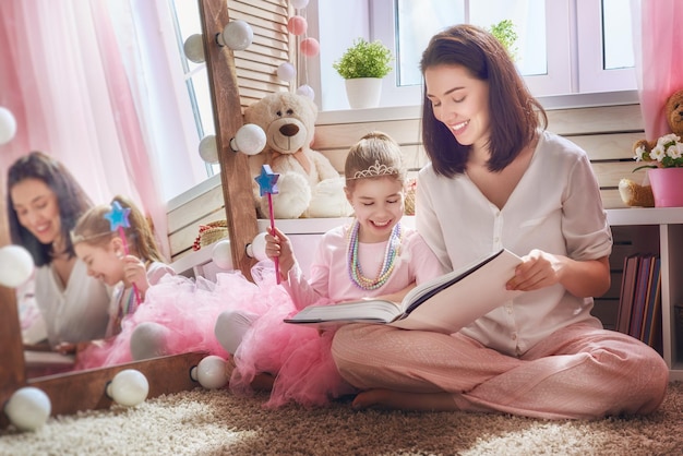 Happy loving family Pretty young mother reading a book to her daughter indoors