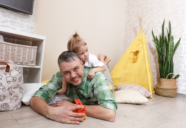 Photo a happy and loving father plays at home with his little daughter