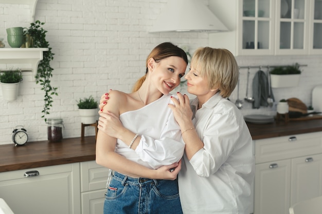 Happy loving older mature mother and grown daughter laughing embracing