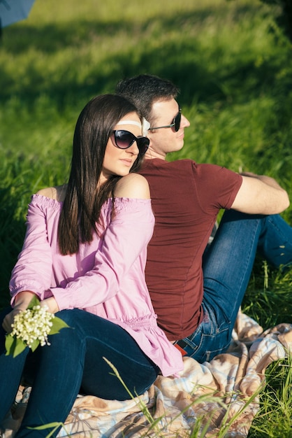 Happy loving young couple spending time in the park sitting on a green lawn on a sunny summer day