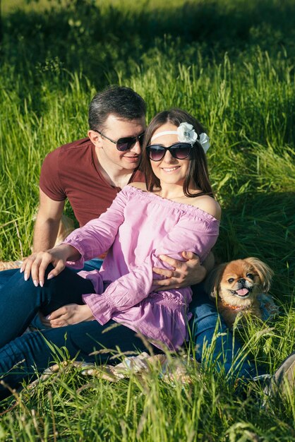 Happy loving young couple spending time in the park sitting on a green lawn on a sunny summer day