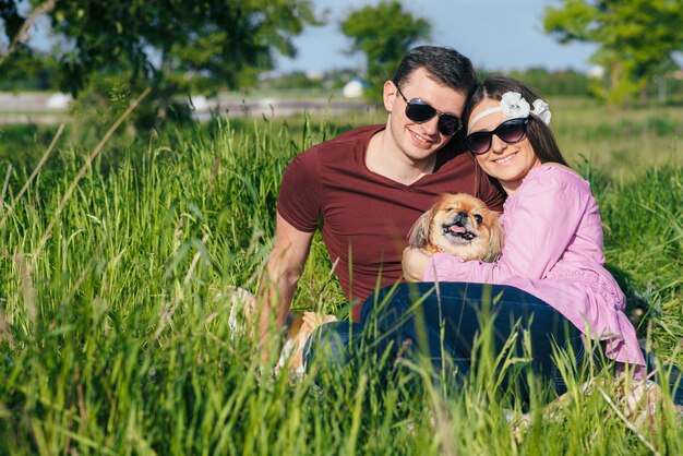 Happy loving young couple spending time in the park sitting on a green lawn on a sunny summer day