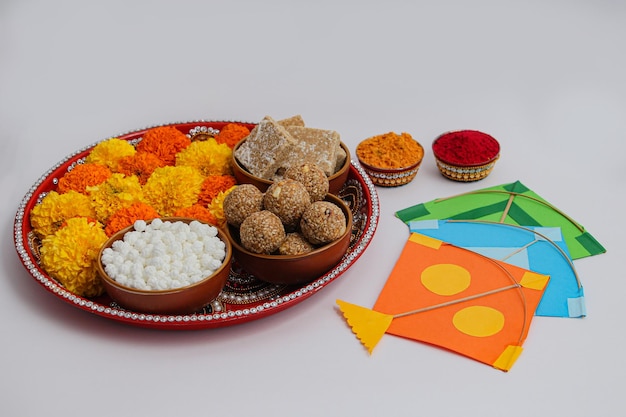 Happy Makar Sankranti, Pongal and Uttarayan with Kite, haldi kum kum bowls and tilgul sweets