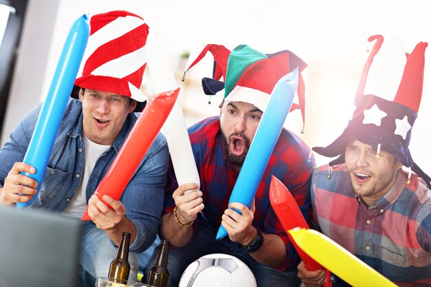 happy male friends cheering and watching sports on tv