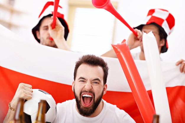 happy male friends cheering and watching sports on tv