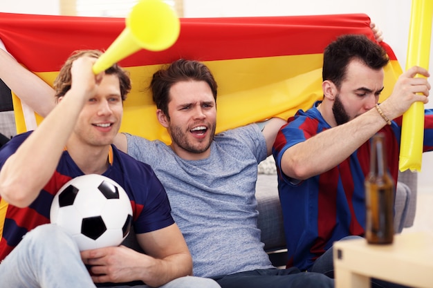 happy male friends cheering and watching sports on tv