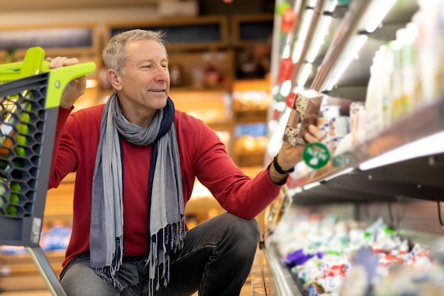 Happy male pensioner buying food at supermarket