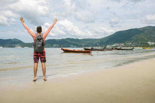 Happy man arms outstretched by the sea enjoying freedom and life people travel vacation holiday concept