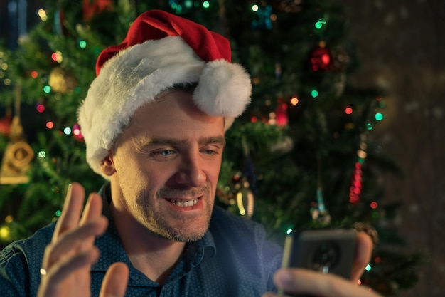 Happy man calling friends for christmas using smartphone celebrating new year at home