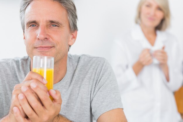 Photo happy man drinking orange juice in kitchen