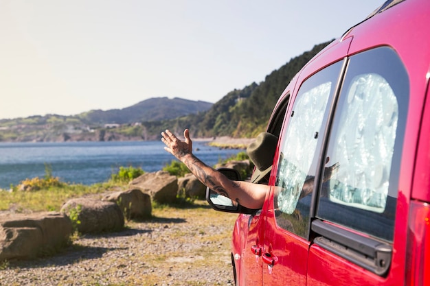 Happy man drives a campervan and sticks his hand out of the window Seaside trip journey and freedom concept