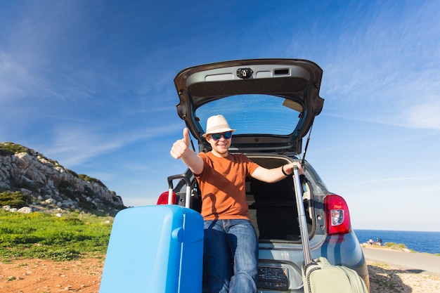 Happy man enjoying road trip and summer vacation. Travel, holidays and people concept