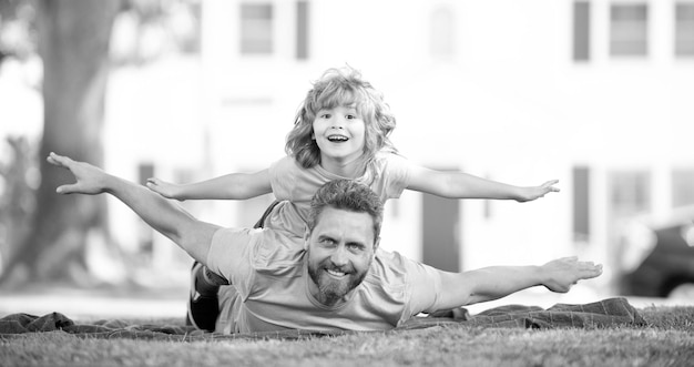 Photo happy man father and boy child pretend flying relaxing on blanket summer outdoors enjoyment