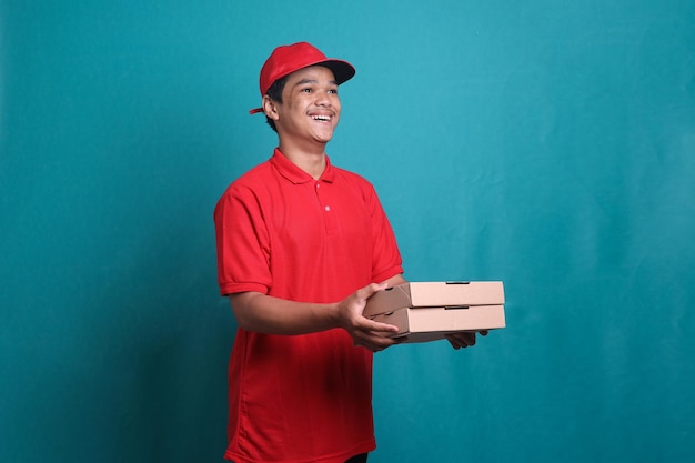 Happy man from delivery service in red t-shirt and cap giving food order and holding two pizza boxes