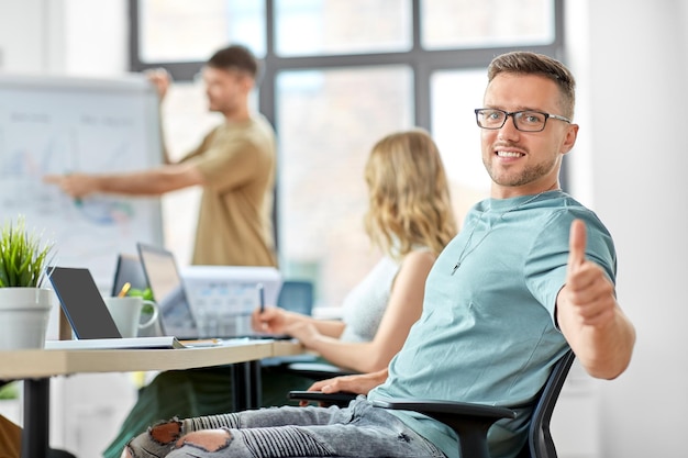 Photo happy man in glasses showing thumbs up at office