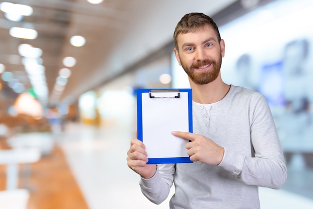 Happy man holding a clipboard and pointing with a finger