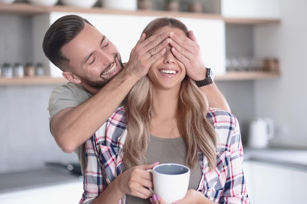 Happy man joking with his girlfriend in the kitchen in the morning