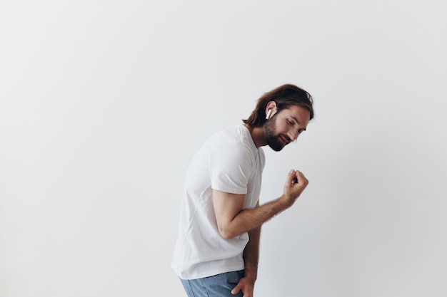 Happy man listening to music and smiling in a white tshirt on a white background happy