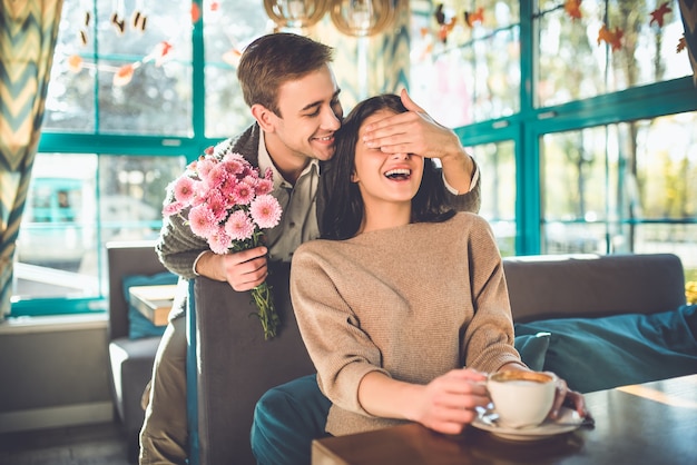 The happy man make a surprise with flowers for a woman in the restaurant