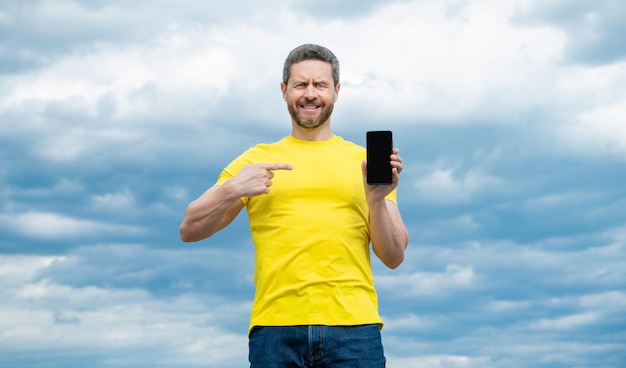 Happy man point finger on screen of smartphone with copy space