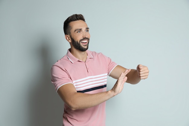 Happy man pretending to drive car on grey background