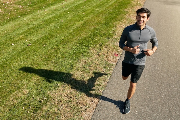 Photo happy man running and fitness with road in cardio workout training or outdoor exercise in countryside active male person young athlete or runner in street for sprint health or wellness in nature