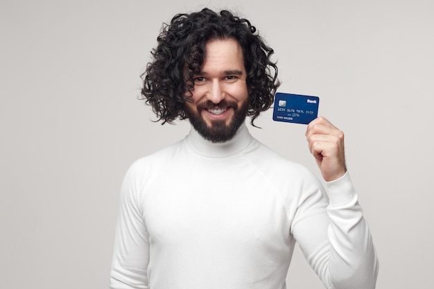 Happy man showing plastic bank card in studio