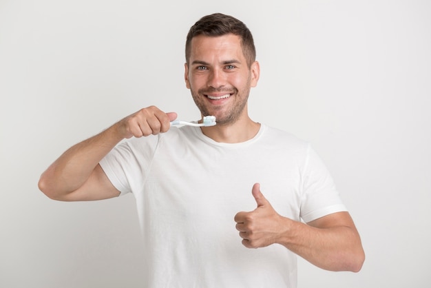 Happy man showing thumb up and holding tooth brush with paste