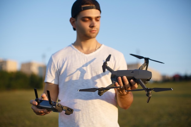 Happy man shows you small compact drone and remote controller pilot holds quadcopter and rc in his