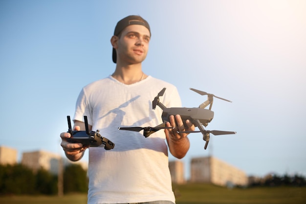 Happy man shows you small compact drone and remote controller pilot holds quadcopter and rc in his