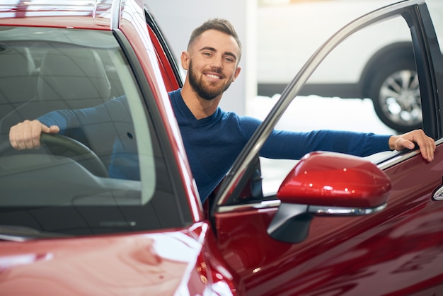 Happy man sitting in car in dealership.