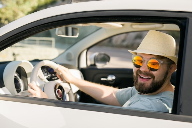 Happy man sitting in white convertible car with beautiful view and having fun travel summer vacation and rental car concept