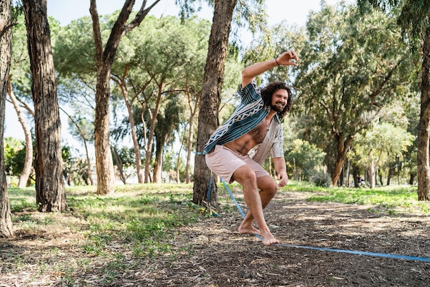 Happy man slacklining in the city park during summer day