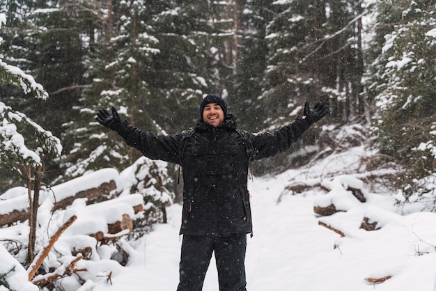 Happy man during a snowfall in the middle of the forest