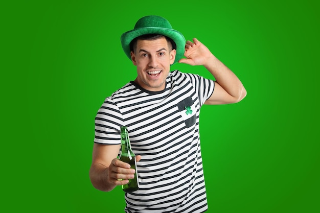 Happy man in St Patrick39s Day outfit with beer on green background