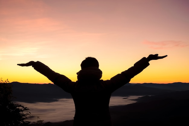 Happy man at sunset or sunrise standing elated with arms raised up