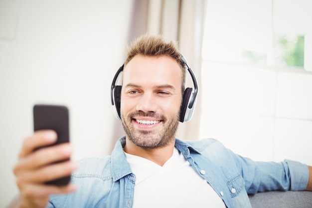 Happy man using mobile phone while listening to music 